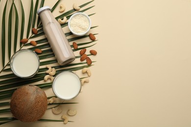Photo of Different vegan milks and ingredients on beige background, flat lay. Space for text