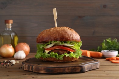 Delicious vegetarian burger and ingredients on wooden table