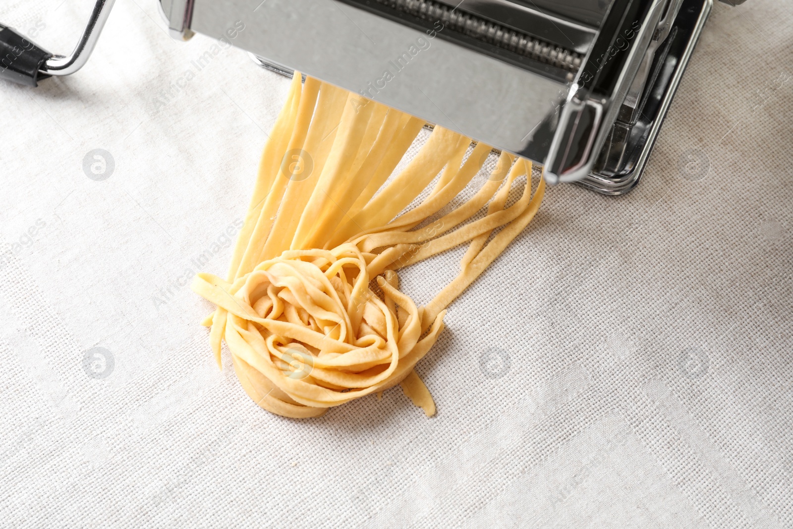 Photo of Pasta maker with wheat dough on light background, top view