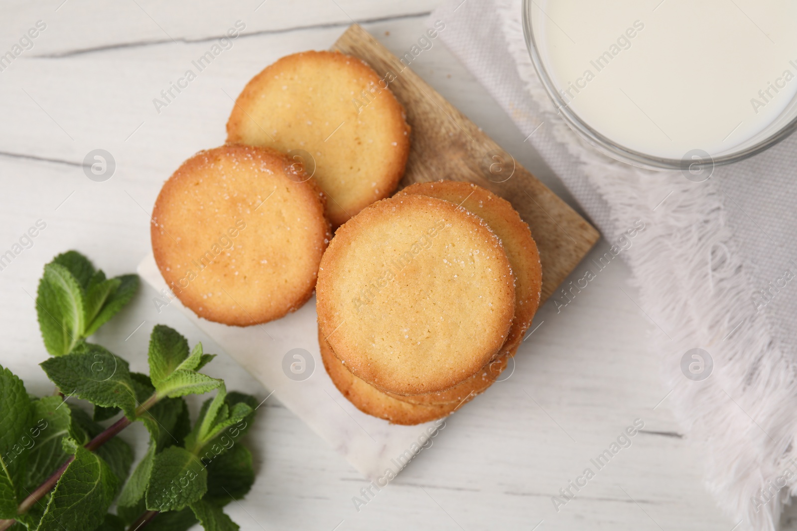 Photo of Tasty sweet sugar cookies and mint on white wooden table, flat lay