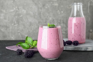 Delicious blackberry smoothie in glassware on black table