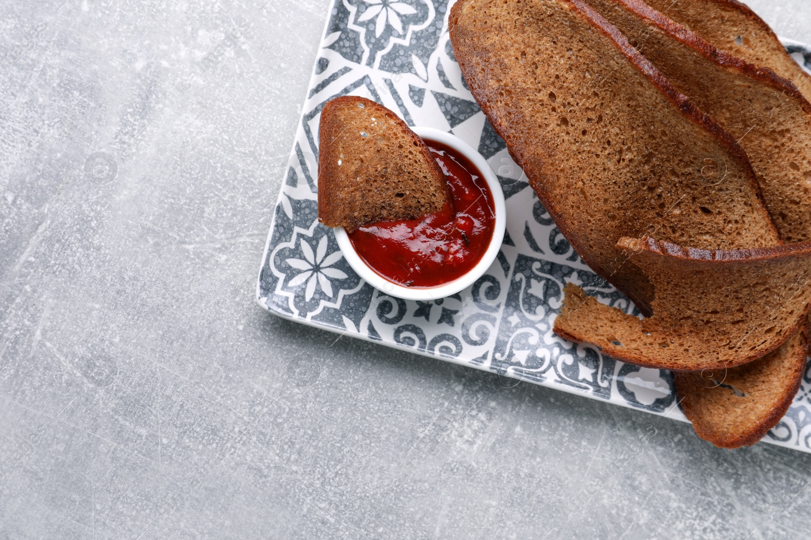 Photo of Plate with crispy rusks and dip sauce on light table, top view. Space for text