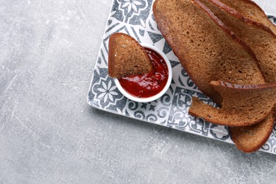 Photo of Plate with crispy rusks and dip sauce on light table, top view. Space for text