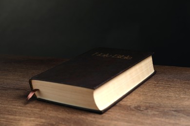 Photo of Hardcover Bible on wooden table. Religious book