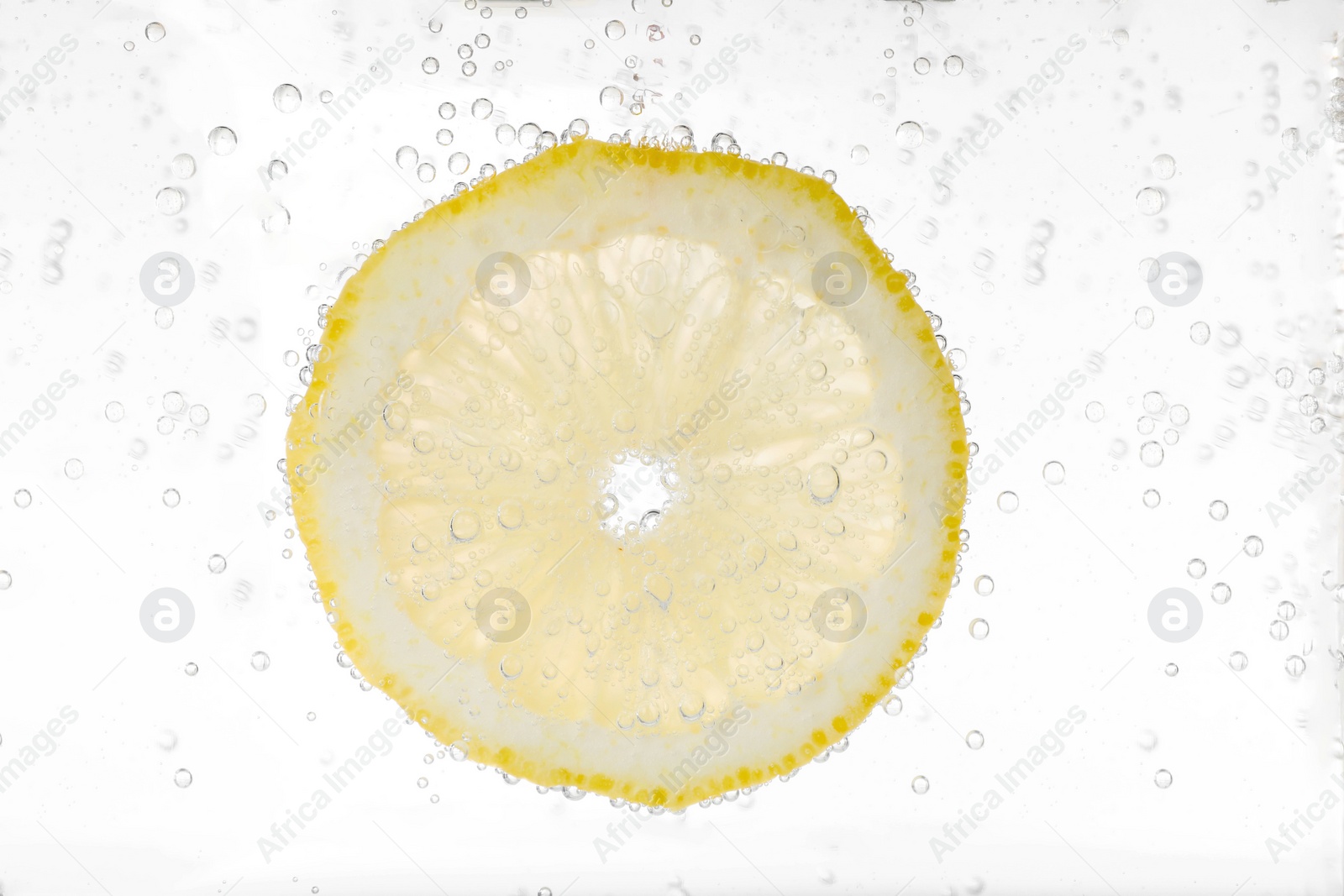 Photo of Juicy lemon slice in soda water against white background, closeup