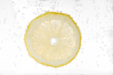 Photo of Juicy lemon slice in soda water against white background, closeup