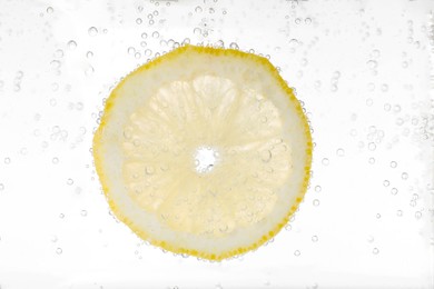 Juicy lemon slice in soda water against white background, closeup