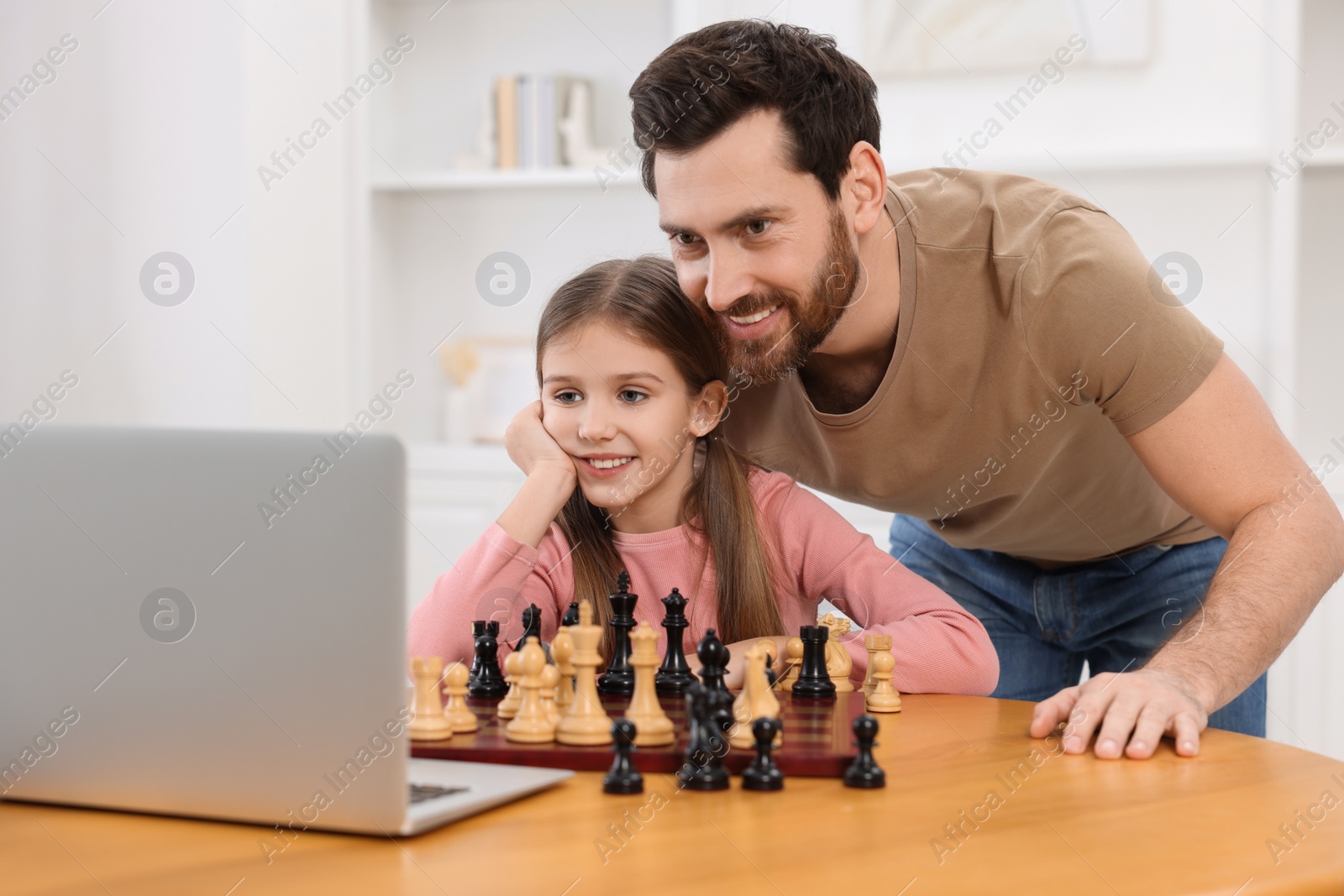 Photo of Father teaching his daughter to play chess following online lesson at home