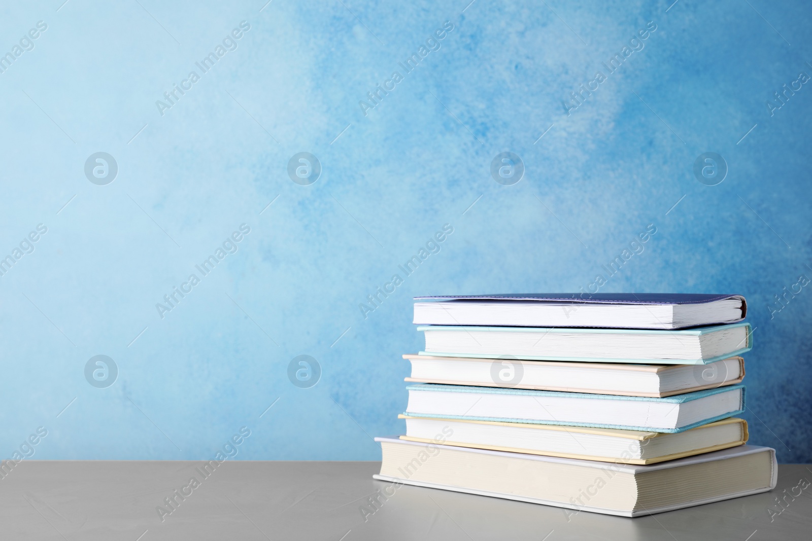 Photo of Stack of hardcover books on table against color background, space for text