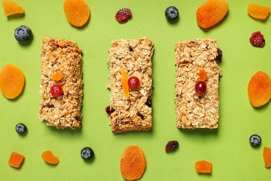 Photo of Tasty granola bars and ingredients on green background, flat lay