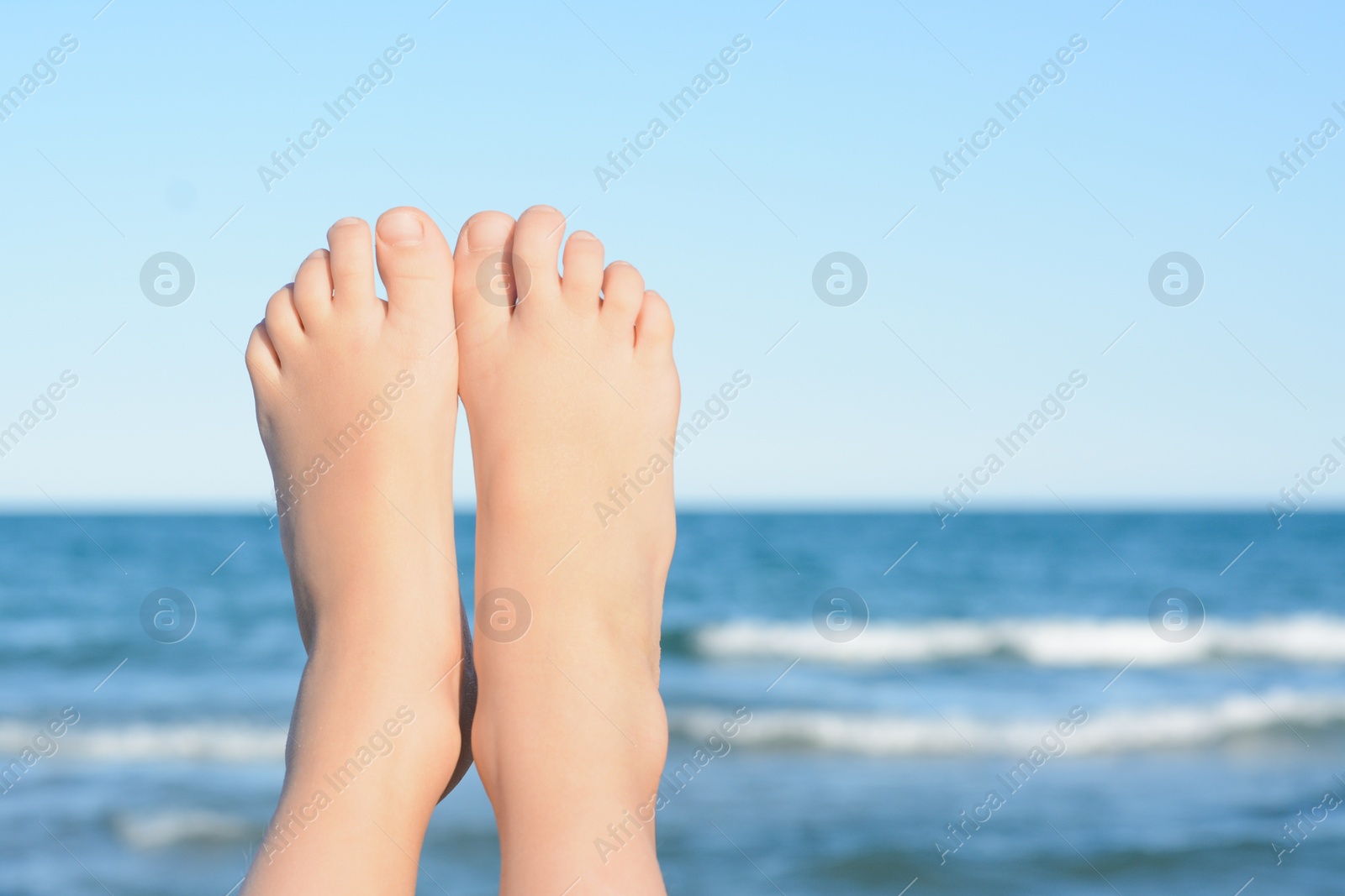 Photo of Child resting near sea, closeup of feet. Space for text