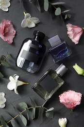 Luxury perfumes and floral decor on black table, flat lay