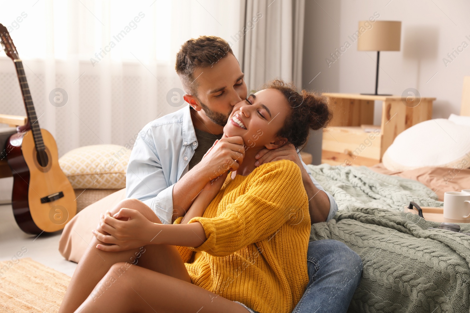 Photo of Lovely couple enjoying time together on floor in bedroom
