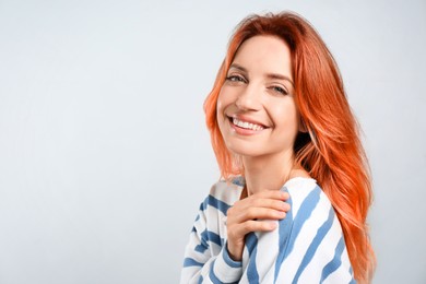 Beautiful woman with long orange hair on light background, space for text