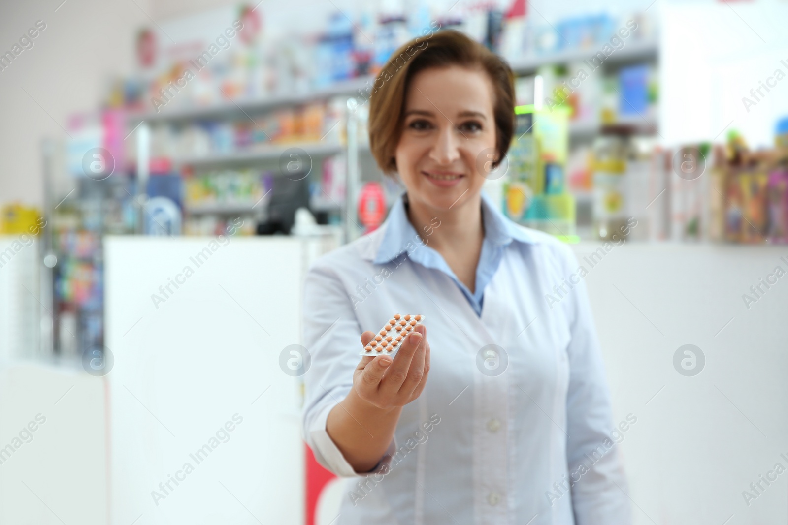 Image of Professional pharmacist in drugstore, focus on hand with pills