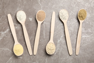 Photo of Spoons with different types of flour on table, top view