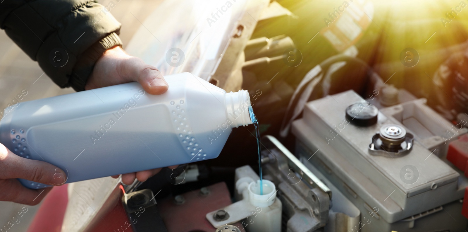 Image of Man filling car radiator with antifreeze outdoors, closeup