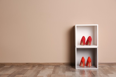 Photo of Modern cabinets with high heeled shoes near color wall, space for text