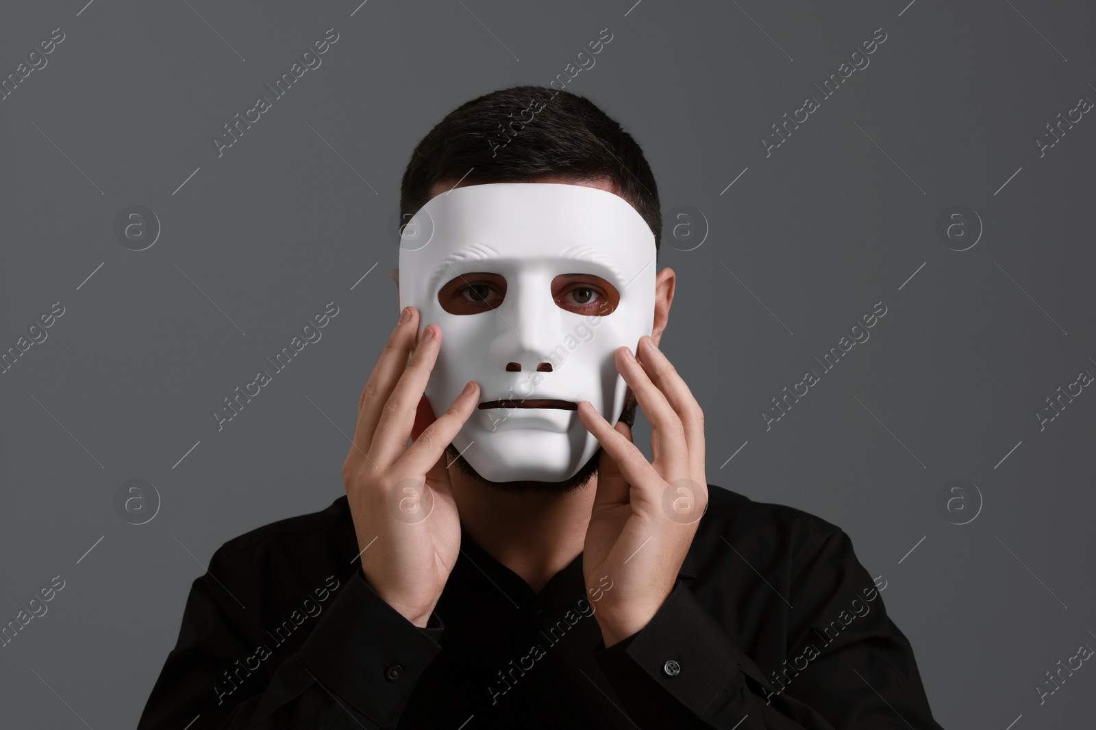 Photo of Multiple personality concept. Man in mask on grey background