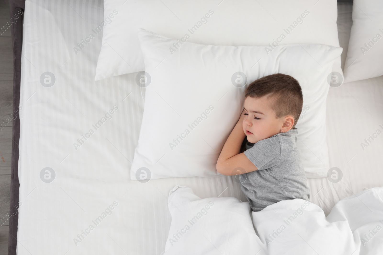 Photo of Cute little boy sleeping in bed, above view. Space for text