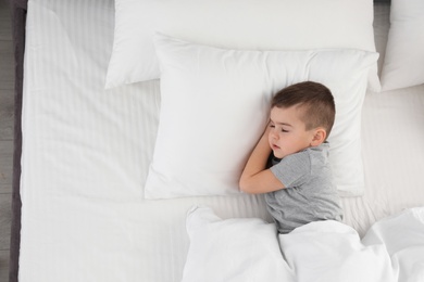 Photo of Cute little boy sleeping in bed, above view. Space for text