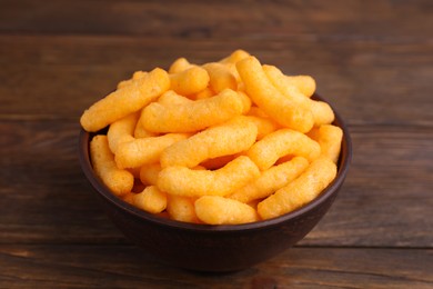 Photo of Bowl with crunchy cheesy corn snack on wooden table, closeup