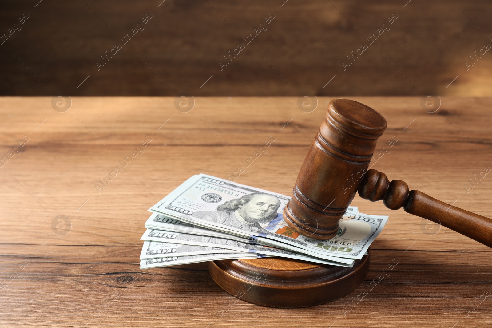 Photo of Judge's gavel and money on wooden table. Space for text