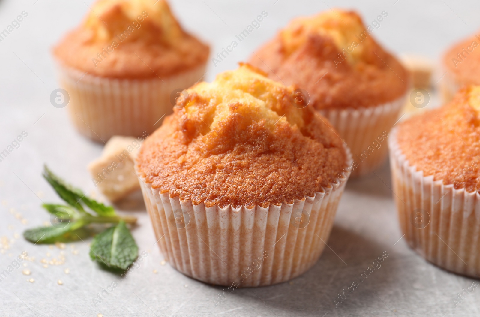 Photo of Delicious sweet muffins and brown sugar on light grey textured table, closeup