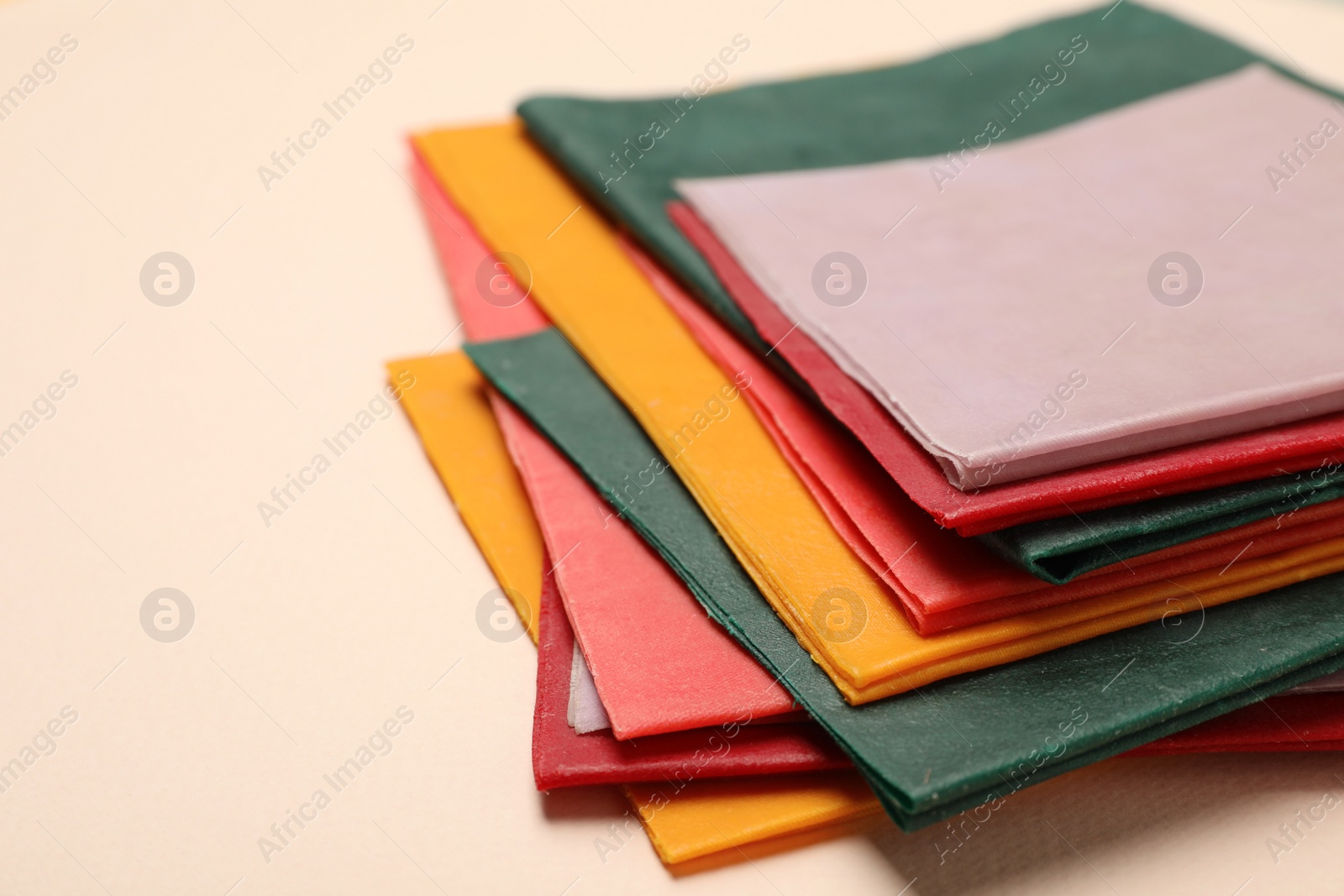 Photo of Colorful reusable beeswax food wraps on beige background, closeup. Space for text