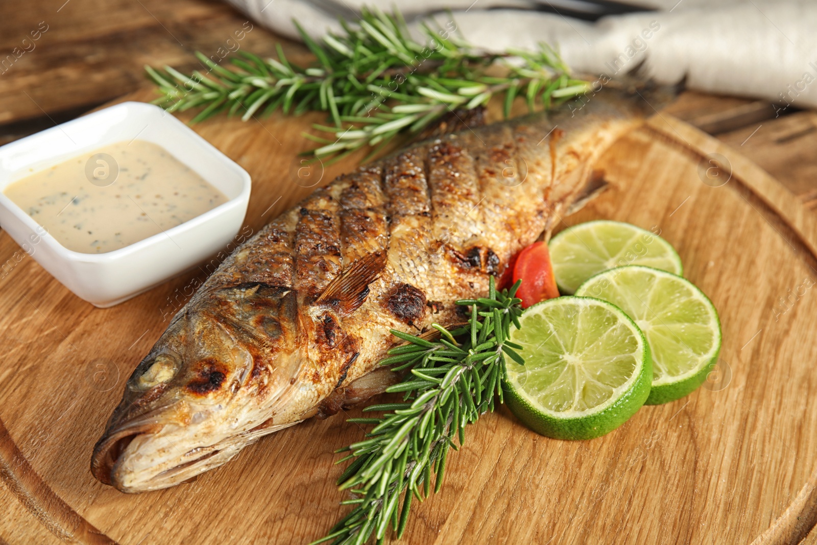 Photo of Delicious grilled fish with lime on wooden board, closeup