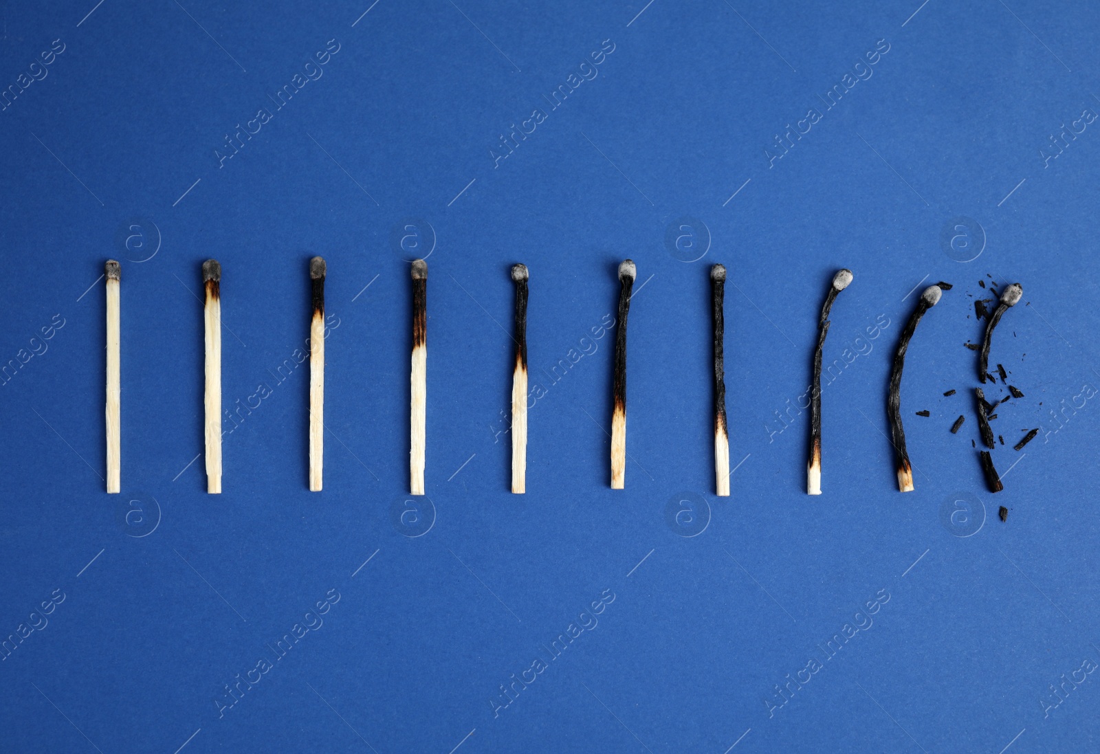 Photo of Different stages of burnt matches on blue background, flat lay