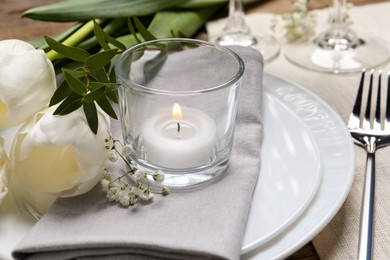 Photo of Stylish setting with cutlery, burning candle and tulips on table, closeup