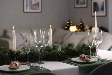 Christmas table setting with burning candles and festive decor in room