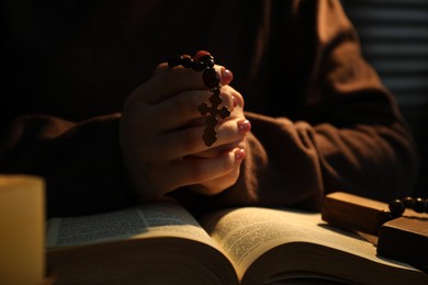 Woman with Bible praying at table, closeup