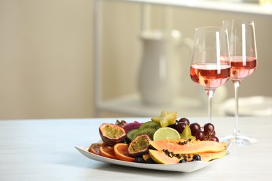 Delicious exotic fruits and wine on white table