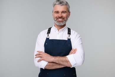 Photo of Happy man wearing kitchen apron on grey background. Mockup for design