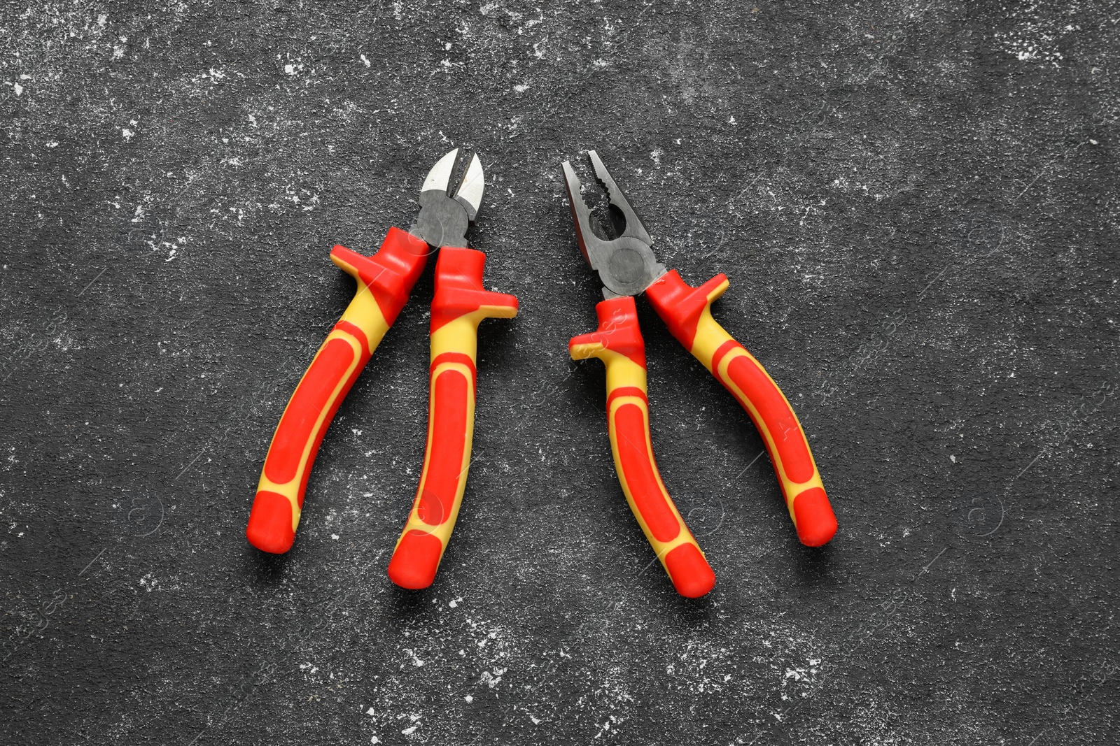 Photo of Pliers on black textured table, flat lay