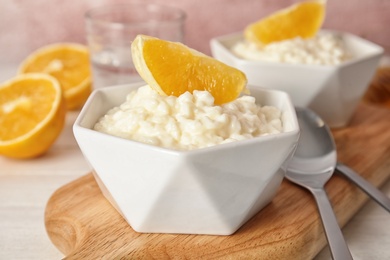 Photo of Creamy rice pudding with orange served on wooden table