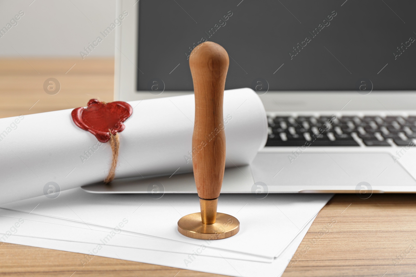 Photo of Notary's public pen and sealed document near laptop on wooden table, closeup