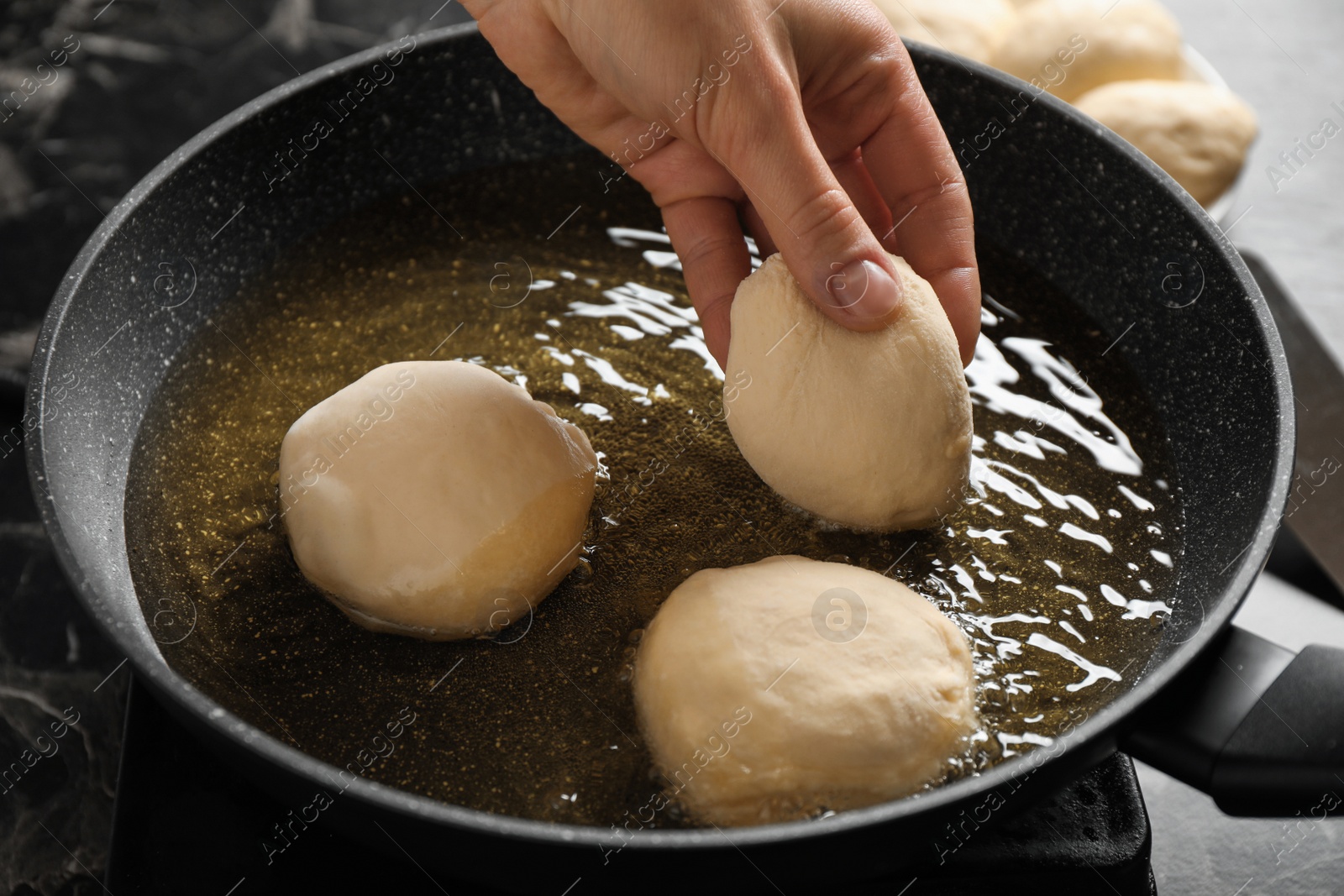 Photo of Woman cooking delicious donuts in oil, closeup