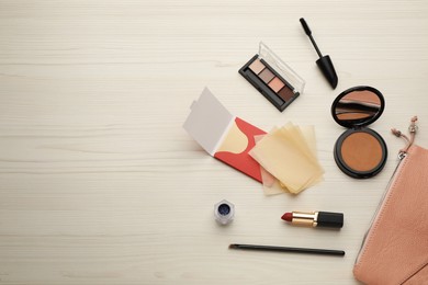 Flat lay composition with facial oil blotting tissues and makeup products on white wooden table, space for text. Mattifying wipes