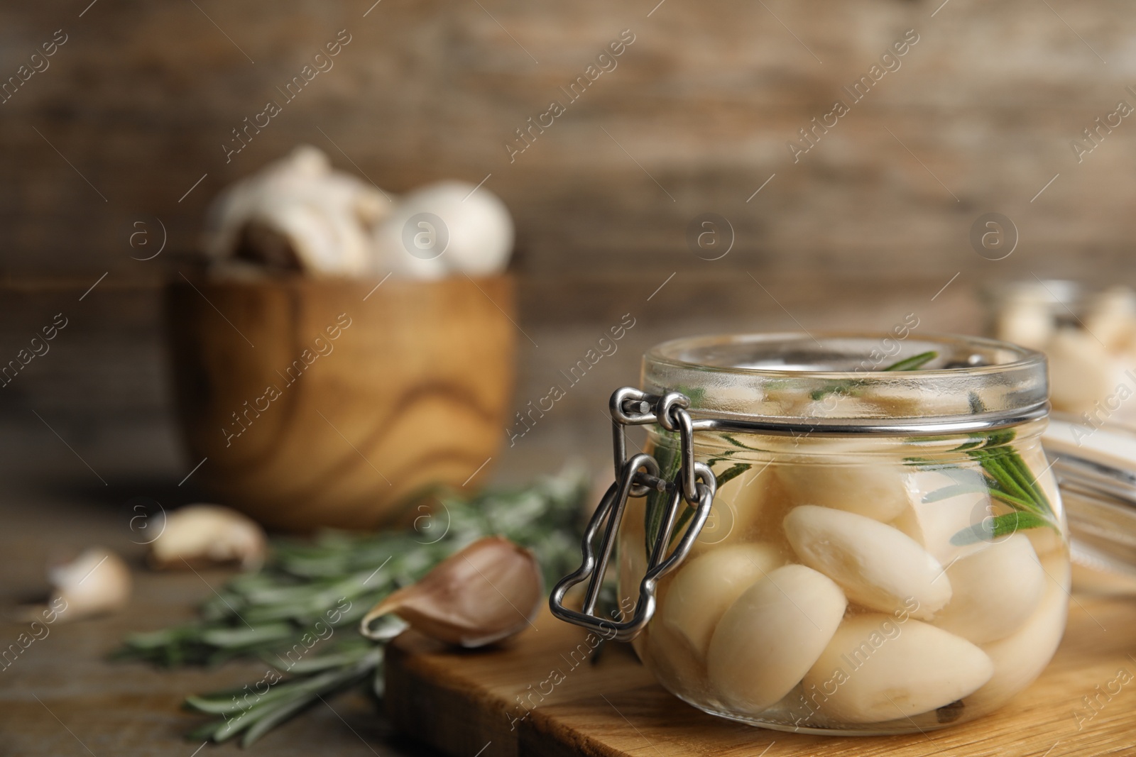 Photo of Composition with jar of pickled garlic on wooden board. Space for text