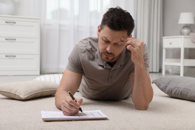 Man solving sudoku puzzle on floor at home