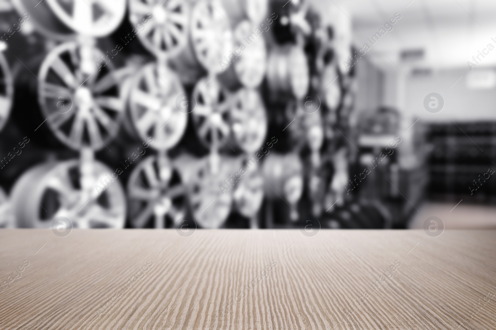 Image of Empty wooden surface and blurred view of car tires in auto store, closeup. Space for text 