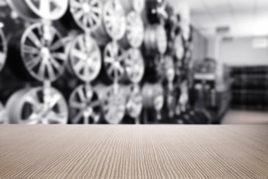 Empty wooden surface and blurred view of car tires in auto store, closeup. Space for text 