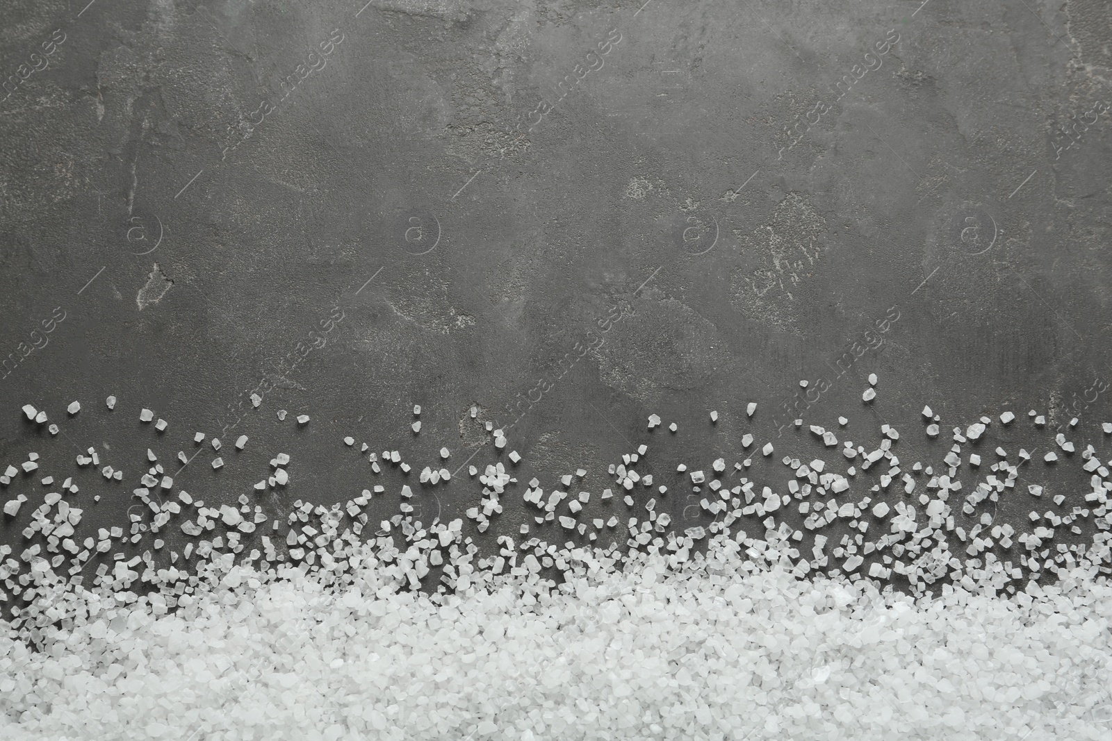 Photo of Natural sea salt on grey table, flat lay. Space for text