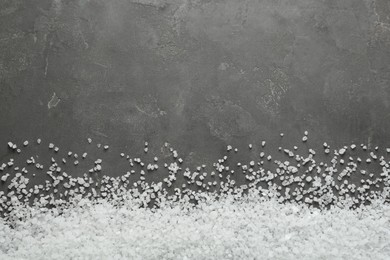 Photo of Natural sea salt on grey table, flat lay. Space for text