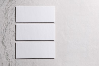 Blank business cards on beige textured background, top view. Mockup for design