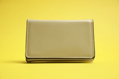 Stylish white leather purse on yellow background