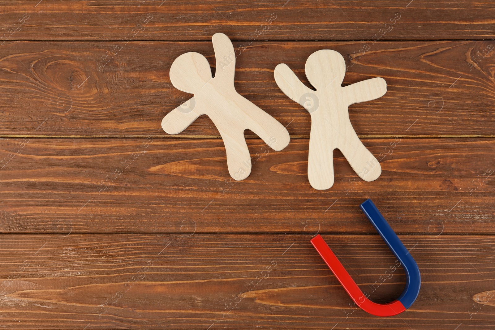 Photo of Magnet and paper people on wooden table, flat lay